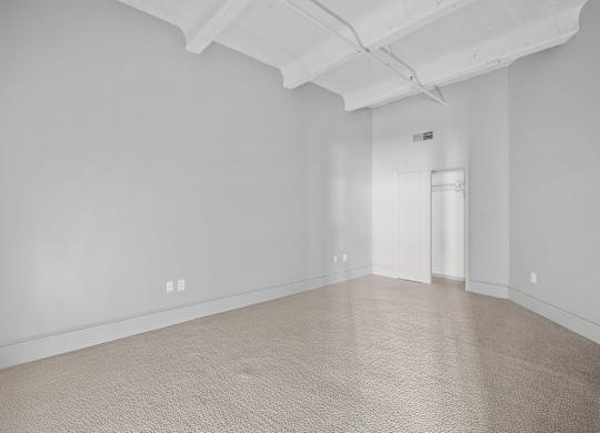 A large empty room with carpeted floor and white walls.
