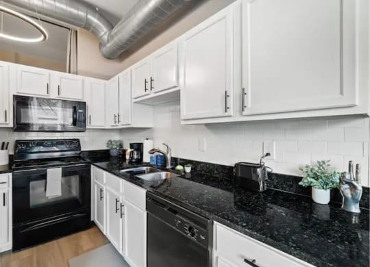 a kitchen with white cabinets and black counter tops