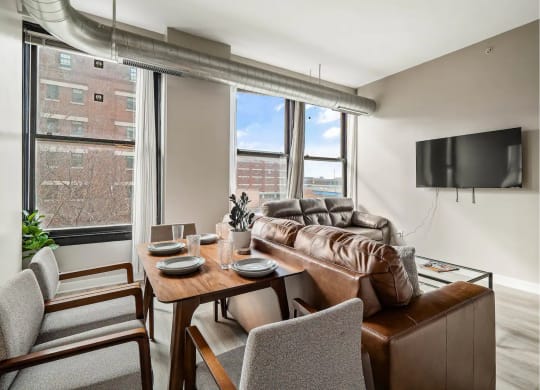 a living room with a leather couch and a table and chairs