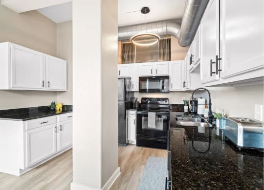 a kitchen with white cabinets and black counter tops