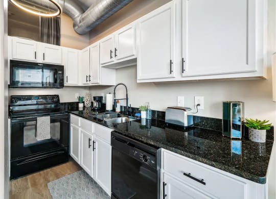 a kitchen with black counter tops and white cabinets