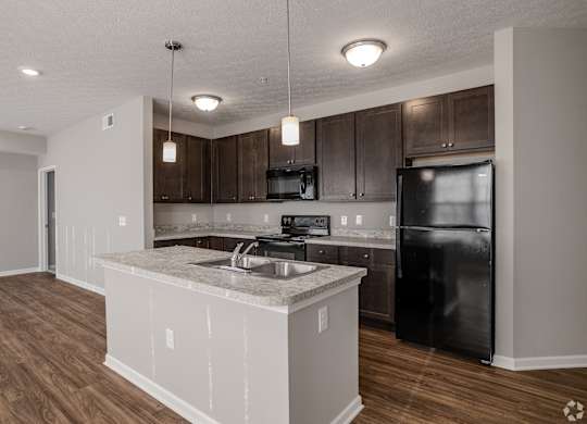 A kitchen with a black refrigerator and wooden cabinets.at The Residences at Akita Lane, Ohio, 43110