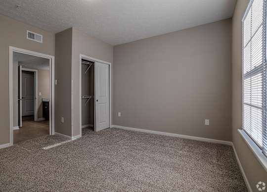 A room with a carpeted floor and two doors leading to other rooms.at The Residences at Akita Lane, Canal Winchester, OH 43110