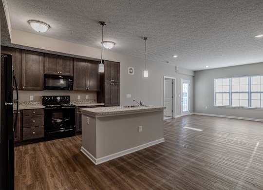 A kitchen with dark wood cabinets and a white island.at The Residences at Akita Lane, Canal Winchester, OH