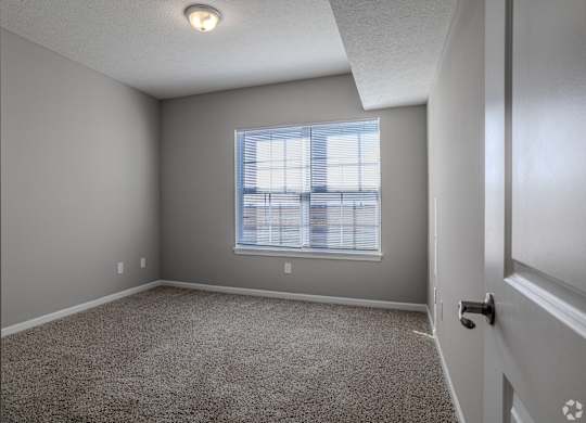 A room with a carpeted floor and a window with blinds.at The Residences at Akita Lane, Canal Winchester, OH 43110