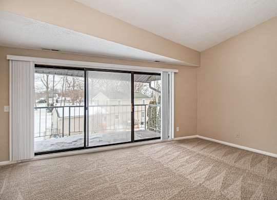 A room with a carpeted floor and a sliding glass door.