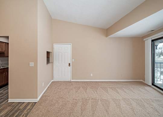 A room with a white door and a window with a view of a balcony.