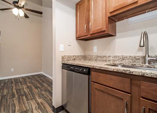 A kitchen with wooden cabinets and a stainless steel dishwasher.