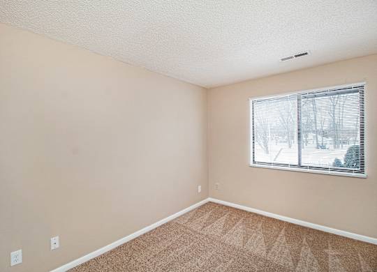A room with a window and carpeted floor.