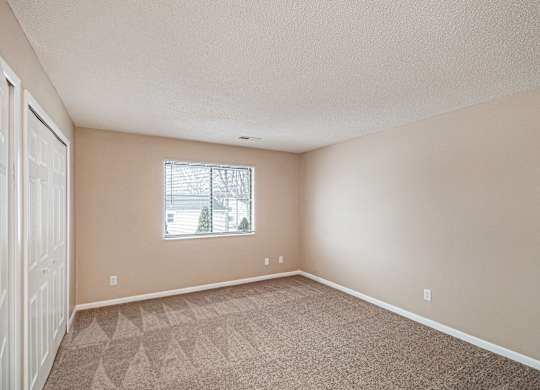 A room with a carpeted floor and a window.
