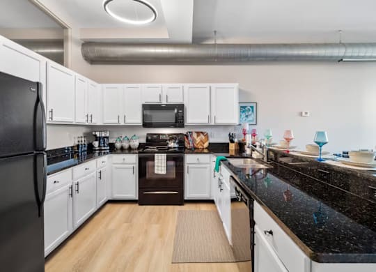 A kitchen with black countertops and white cabinets.