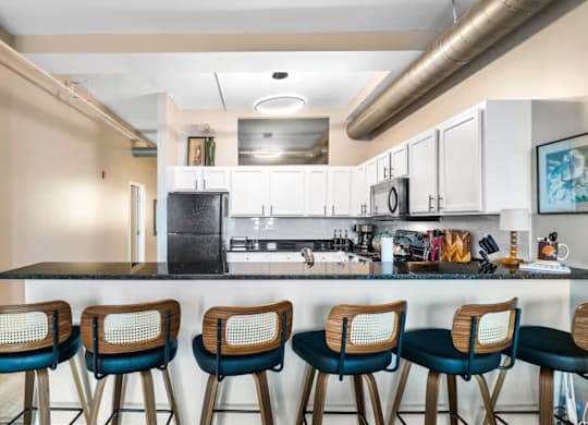 A kitchen with a bar area featuring a black counter and blue barstools.