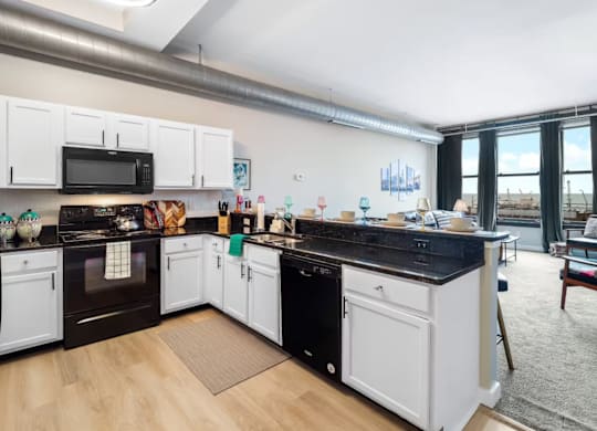 A kitchen with black countertops and white cabinets.
