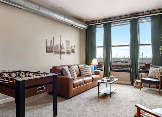 A living room with a foosball table, couch, and pictures on the wall.