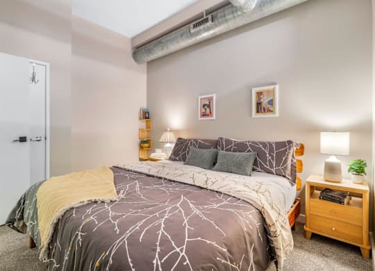 A bedroom with a bed, nightstand, and wall art.