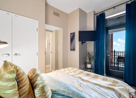 A bedroom with a bed, a window with blue curtains, and a white wardrobe.