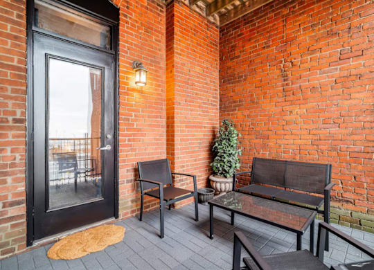 A black door is on the left of a brick wall with a bench and a table in front of it.