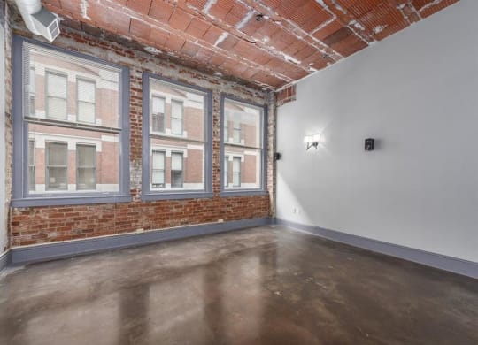 an empty room with a brick wall and three large windows at East 4th Street, Cleveland, OH, 44115