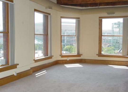 an empty room with three windows and a carpeted floor