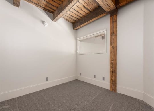 a bedroom with white walls and a ceiling with wooden beams
