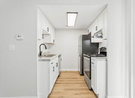 A white kitchen with a black fridge and stove.