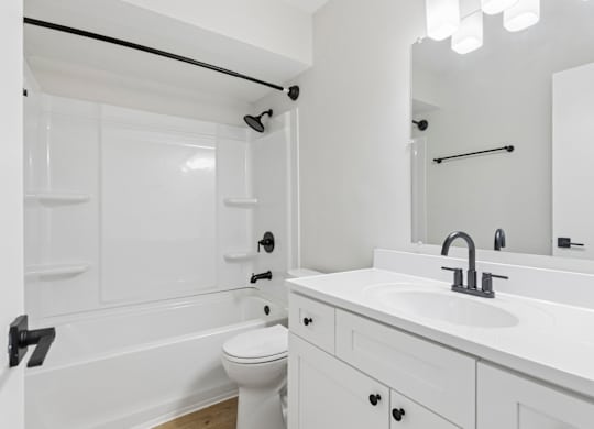 A white bathroom with a toilet, sink, and bathtub.
