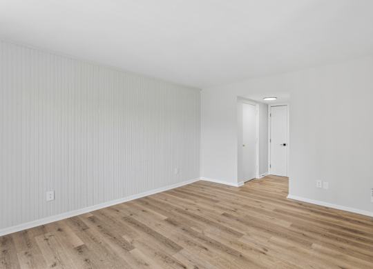 A room with wooden flooring and white walls.