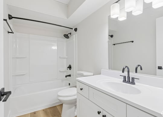 A white bathroom with a toilet, sink, and bathtub.