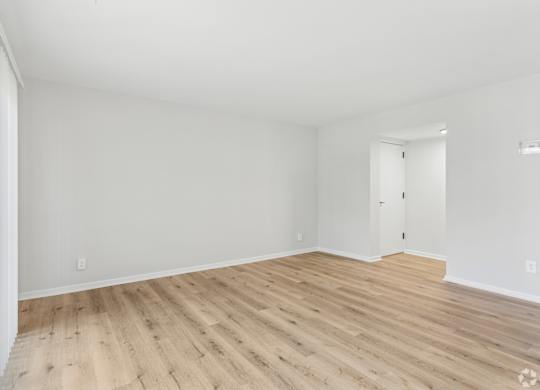 A room with wooden flooring and white walls.
