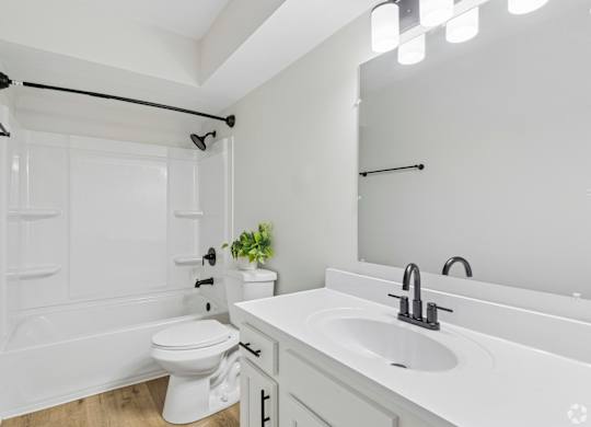 A white bathroom with a toilet, sink, and mirror.