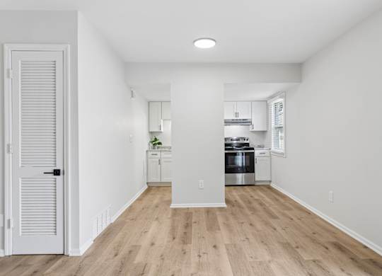 A kitchen with white walls and wooden floors.