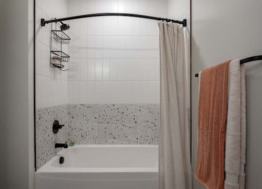A white bathtub with a shower curtain and a towel hanging on a rack at The Park Apartments, Cleveland , OH, 44113