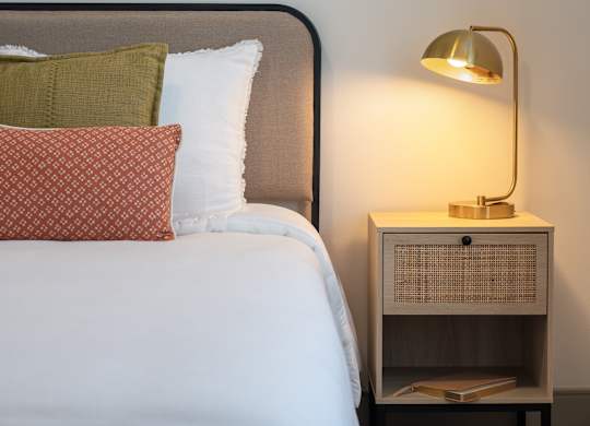 A bedroom with a bed, nightstand, and a motel poster on the wall at The Park Apartments, Ohio