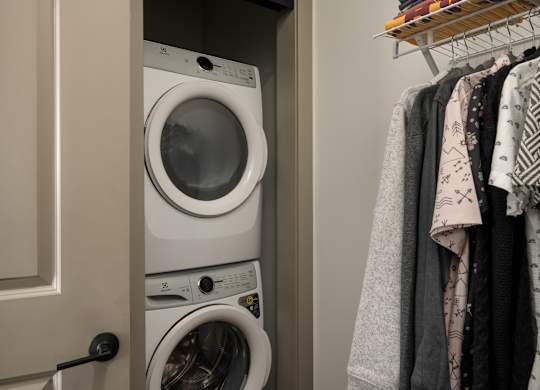 A white washing machine is in a cabinet under a white door at The Park Apartments, Cleveland
