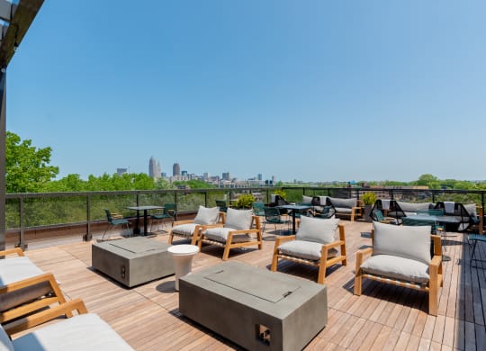 an outdoor deck with lounge chairs and fire pits with a view of the Cleveland skyline at TREO Apartments, Cleveland, 44116
