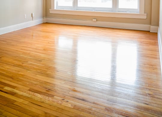 an empty living room with wood floors and a large window