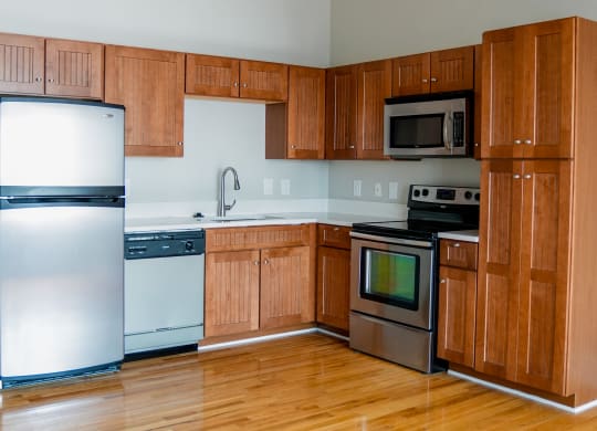 an empty kitchen with wooden cabinets and stainless steel appliances