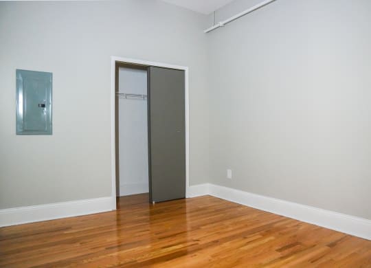 an empty room with wood floors and a closet