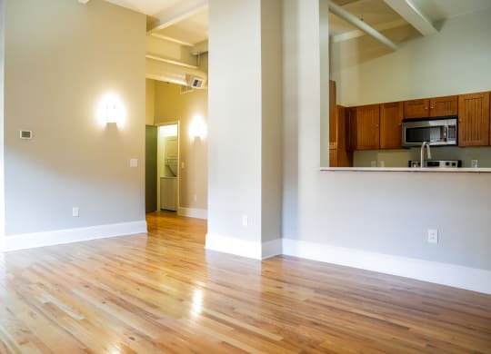 an empty living room with wood floors and a kitchen