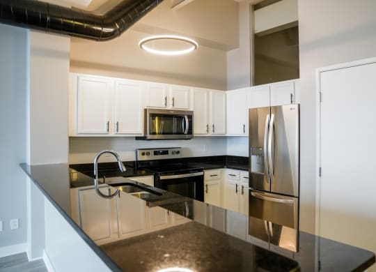 a kitchen with black counter tops and stainless steel appliances