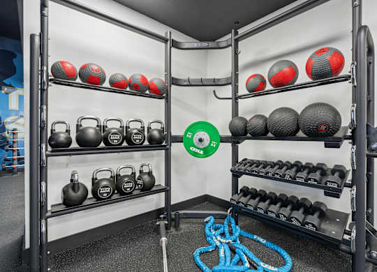 A gym with a rack of kettlebells and dumbbells.