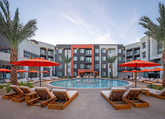 A pool surrounded by palm trees and lounge chairs.