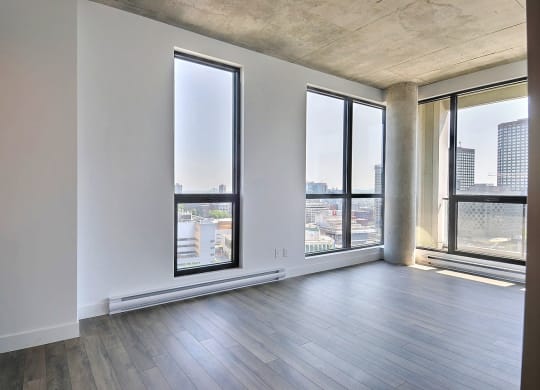 an empty living room with large windows and a city view