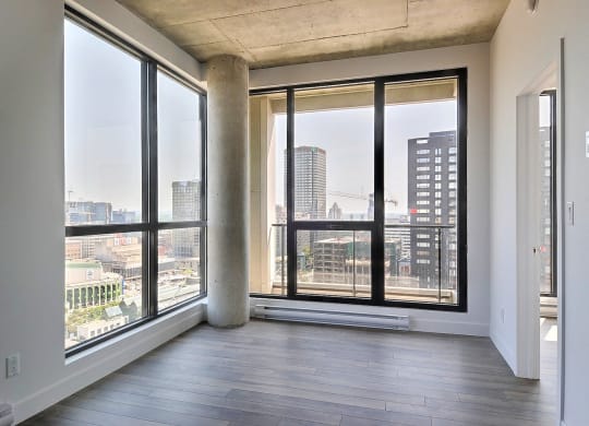 an empty living room with large windows and a city view