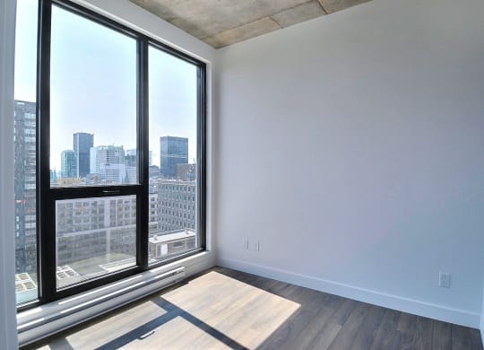 an empty living room with large windows and a city view