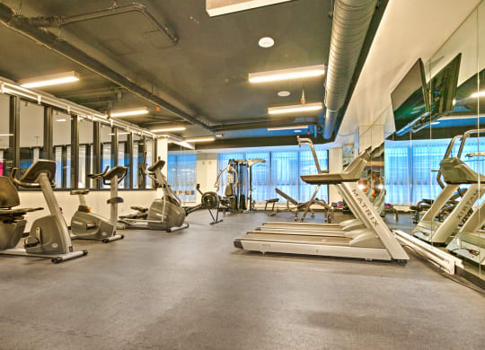 a gym with cardio equipment and weights on the floor