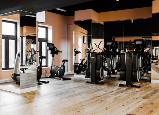 a gym with cardio machines and weights on a wooden floor