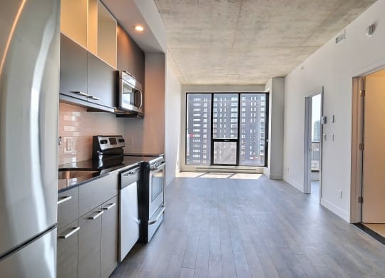 an empty apartment with a kitchen and a door to a balcony