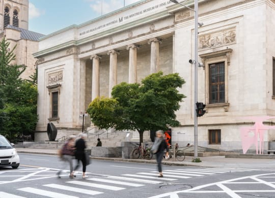 people crossing the street in front of a large building