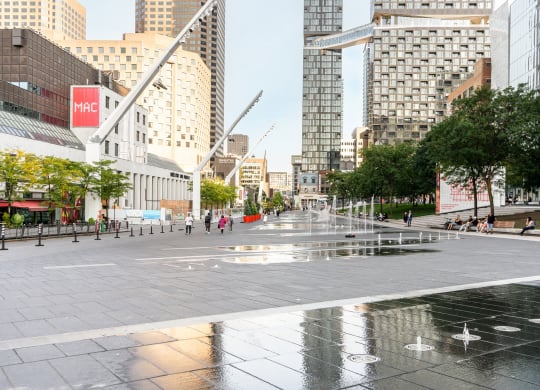 a city square with water fountains and tall buildings
